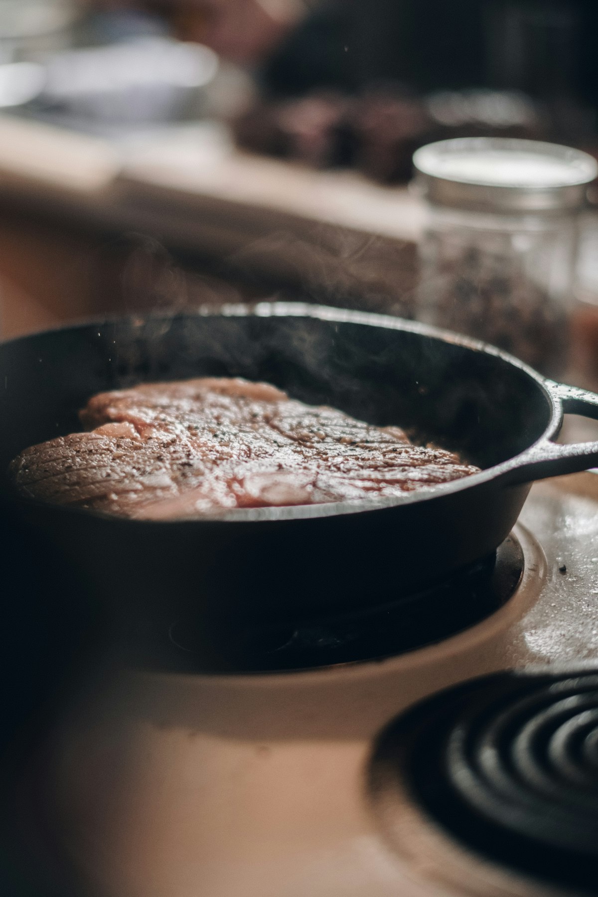 Steak searing in a black skillet on an electric stove
