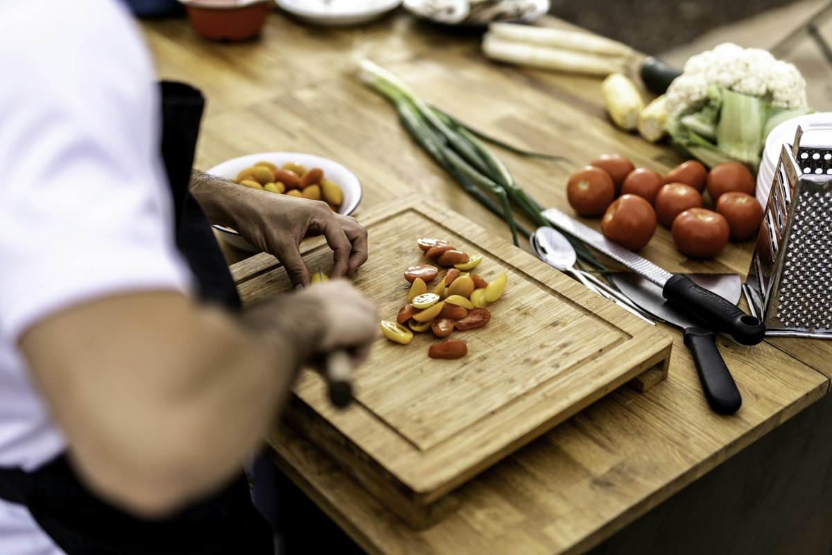 Person chopping vegetables on a wooden cutting board