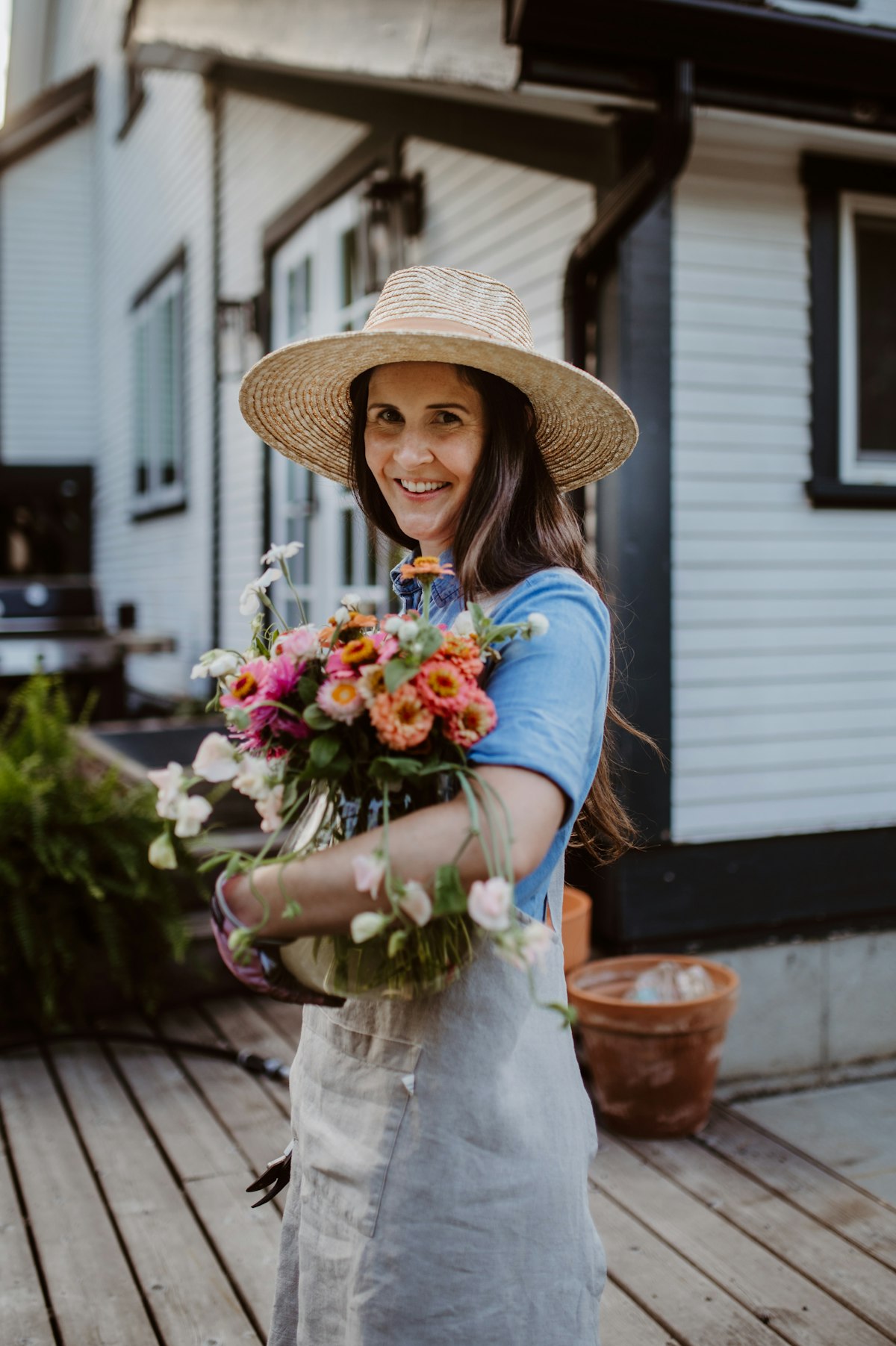 Woman in a straw hat holding a bouquet in a home garden