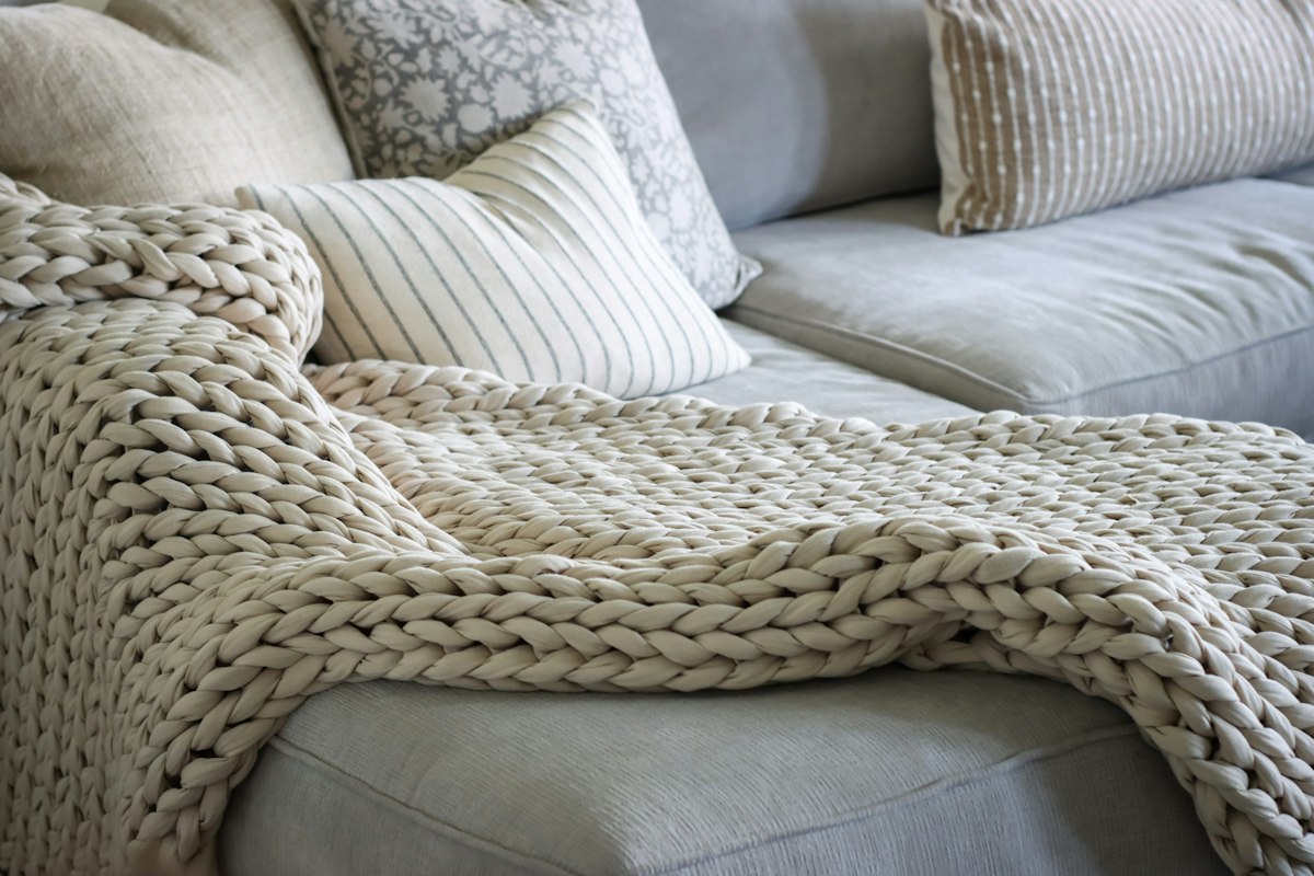 Chunky knit throw blanket draped over a grey sofa